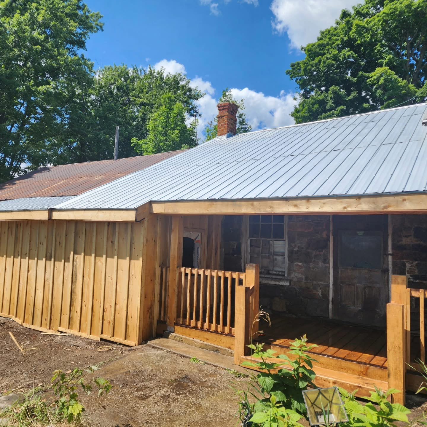 New standing-seam metal roof and cedar side wall on restored farmhouse