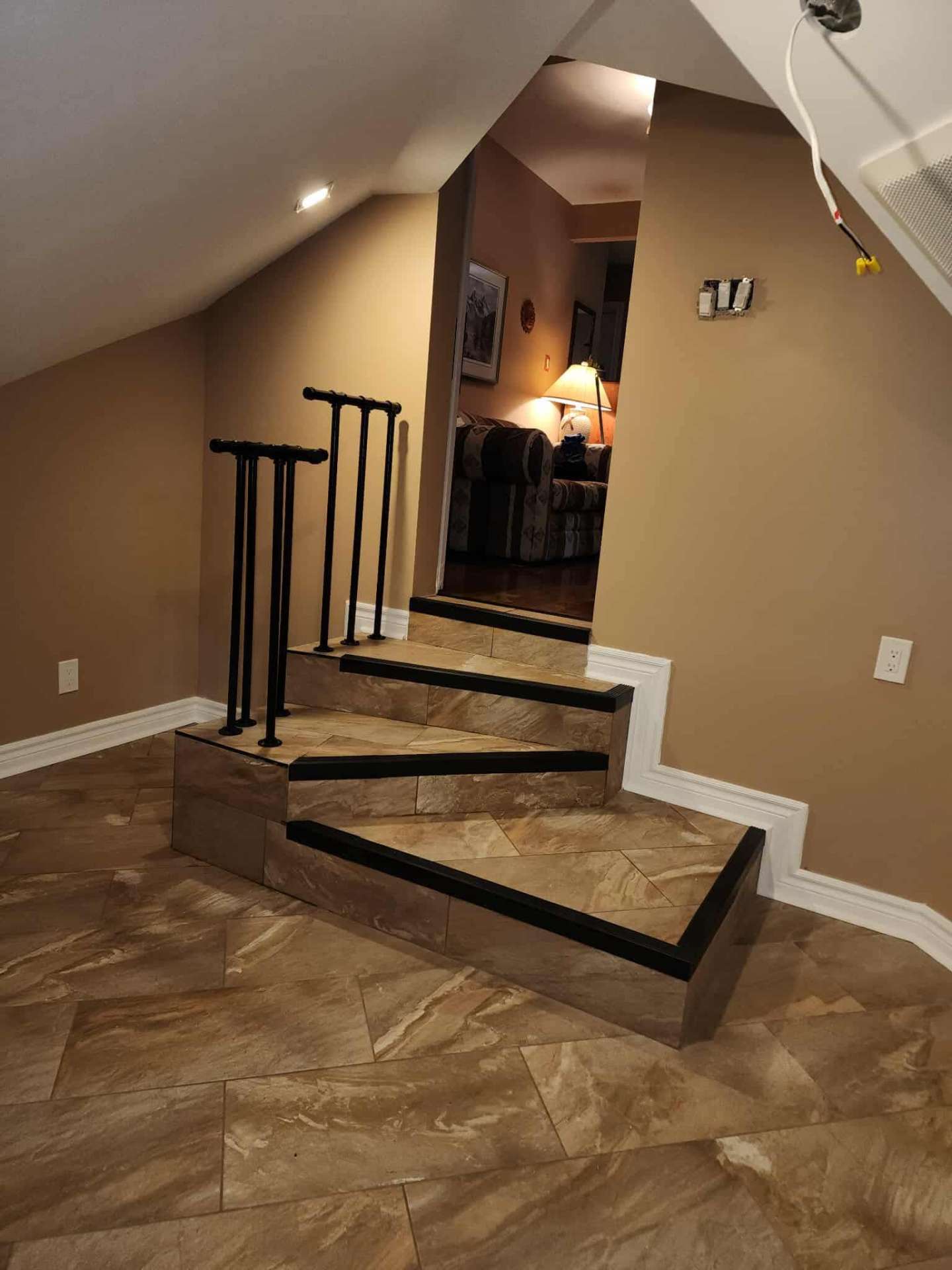 New tiled staircase with black railings connecting the suite to the closet addition